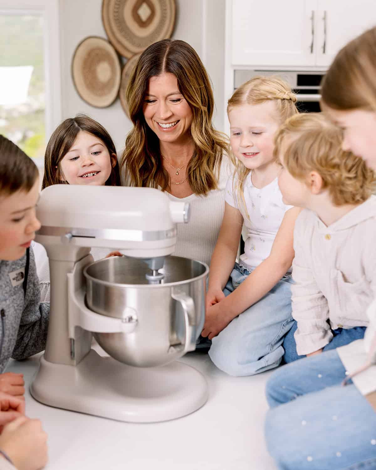a mom and her 5 kids gathered around a standing mixer