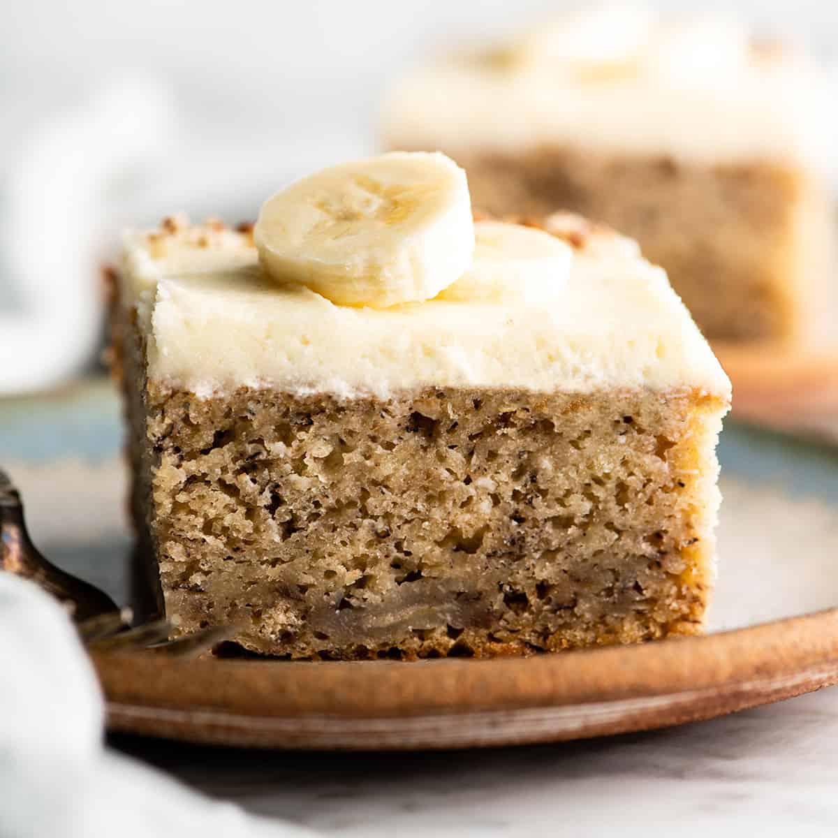 front view of a piece of banana cake with cream cheese frosting