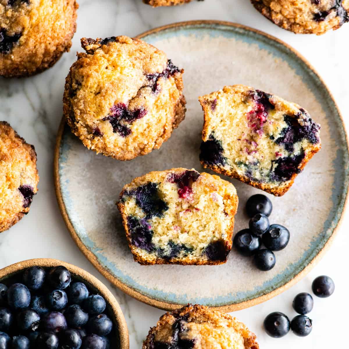 overhead view of a blueberry muffin cut in half with other whole muffins around it