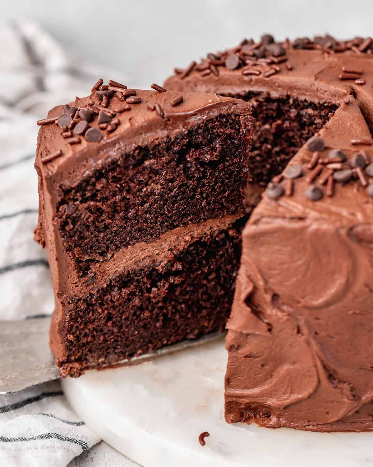a slice of Chocolate Cake being taken out of the whole cake with a cake server