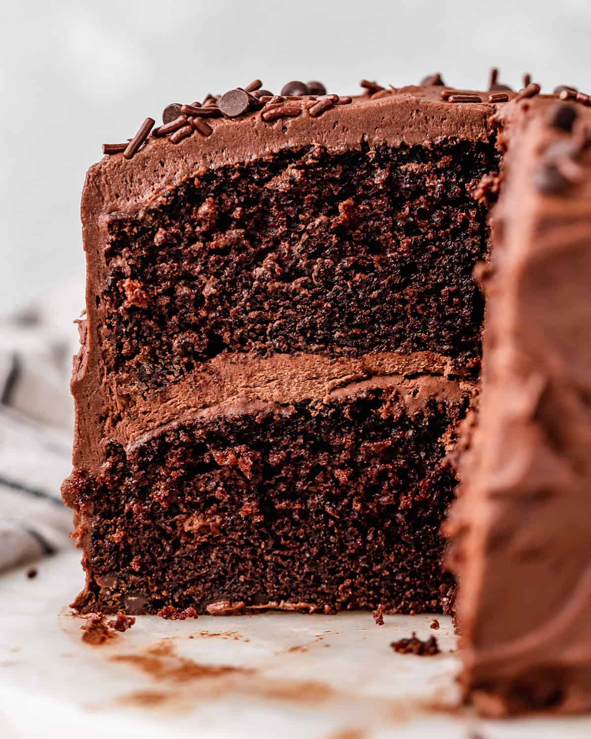 two-layer chocolate cake on a plate with a slice cut out of it so you can see the inside. 