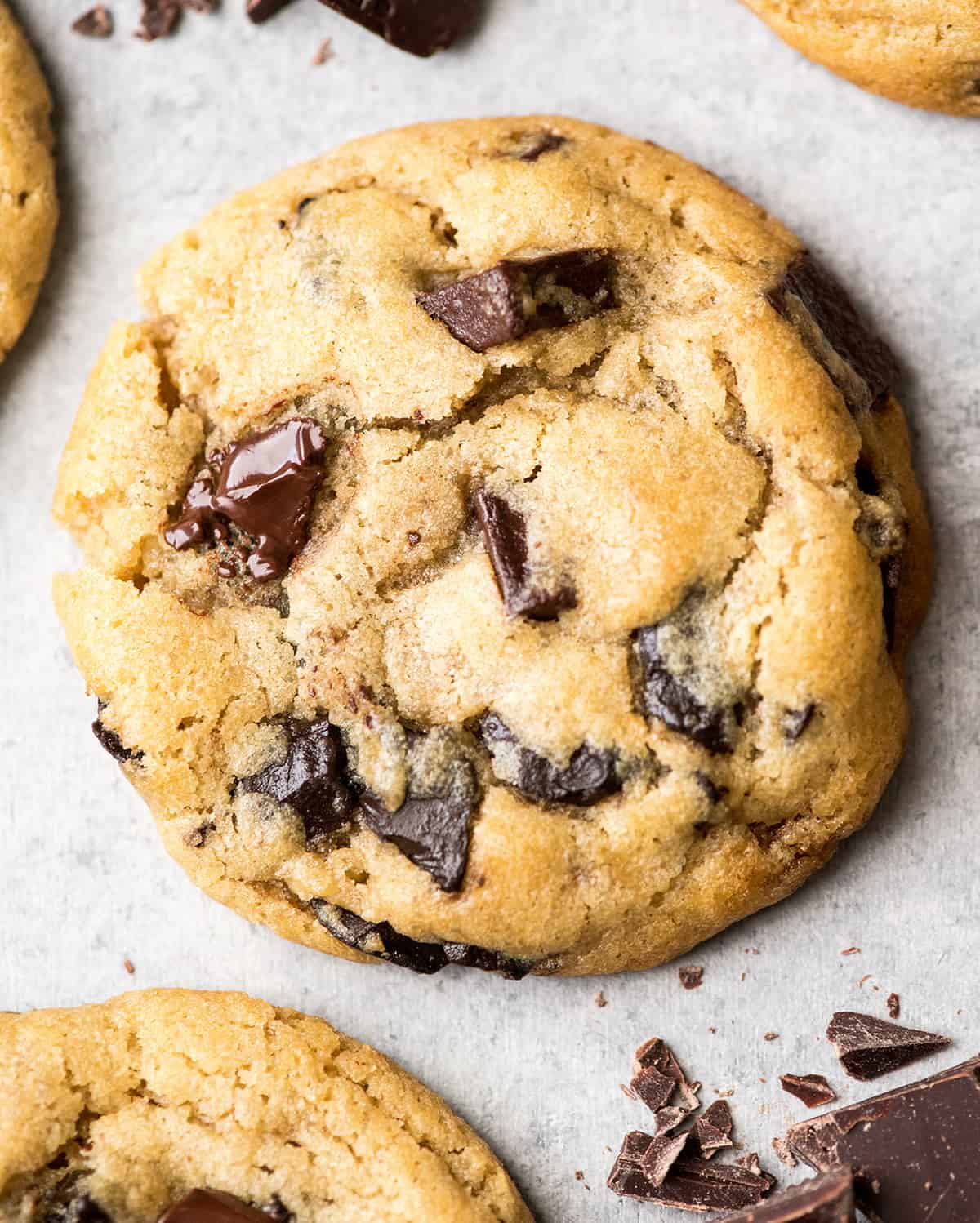 This is the best chocolate chip cookie recipe ever. No funny ingredients, no chilling time, etc. Just a simple, straightforward, amazingly delicious, doughy yet still fully cooked, chocolate chip cookie that turns out perfectly every single time! #cookies #chocolatechipcookies #baking #recipe #chocolate up close overhead view of one chocolate chip cookie