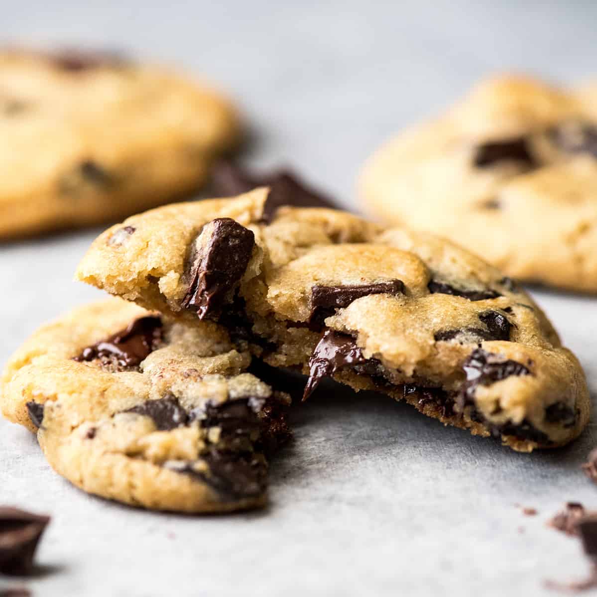 This is the best chocolate chip cookie recipe ever. No funny ingredients, no chilling time, etc. Just a simple, straightforward, amazingly delicious, doughy yet still fully cooked, chocolate chip cookie that turns out perfectly every single time! #cookies #chocolatechipcookies #baking #recipe #chocolate Front view of a chocolate chip cookie cut in half with melty chocolate chips