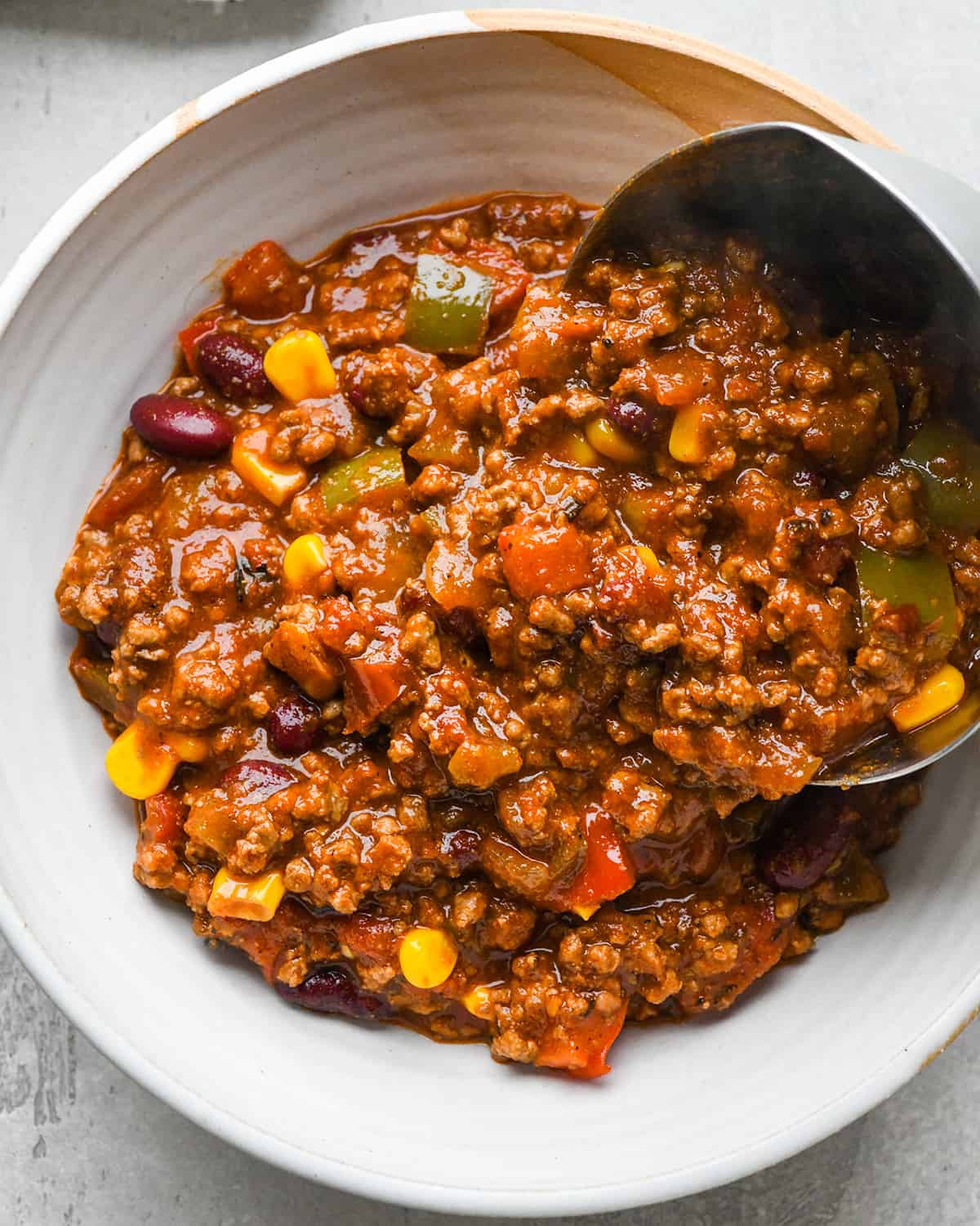 a ladle pouring homemade chili into a bowl 