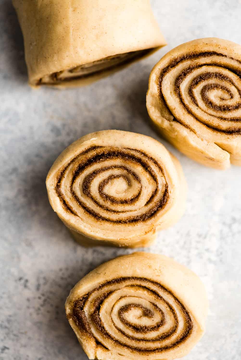 overhead photo showing how to make cinnamon rolls - dough being cut into rolls