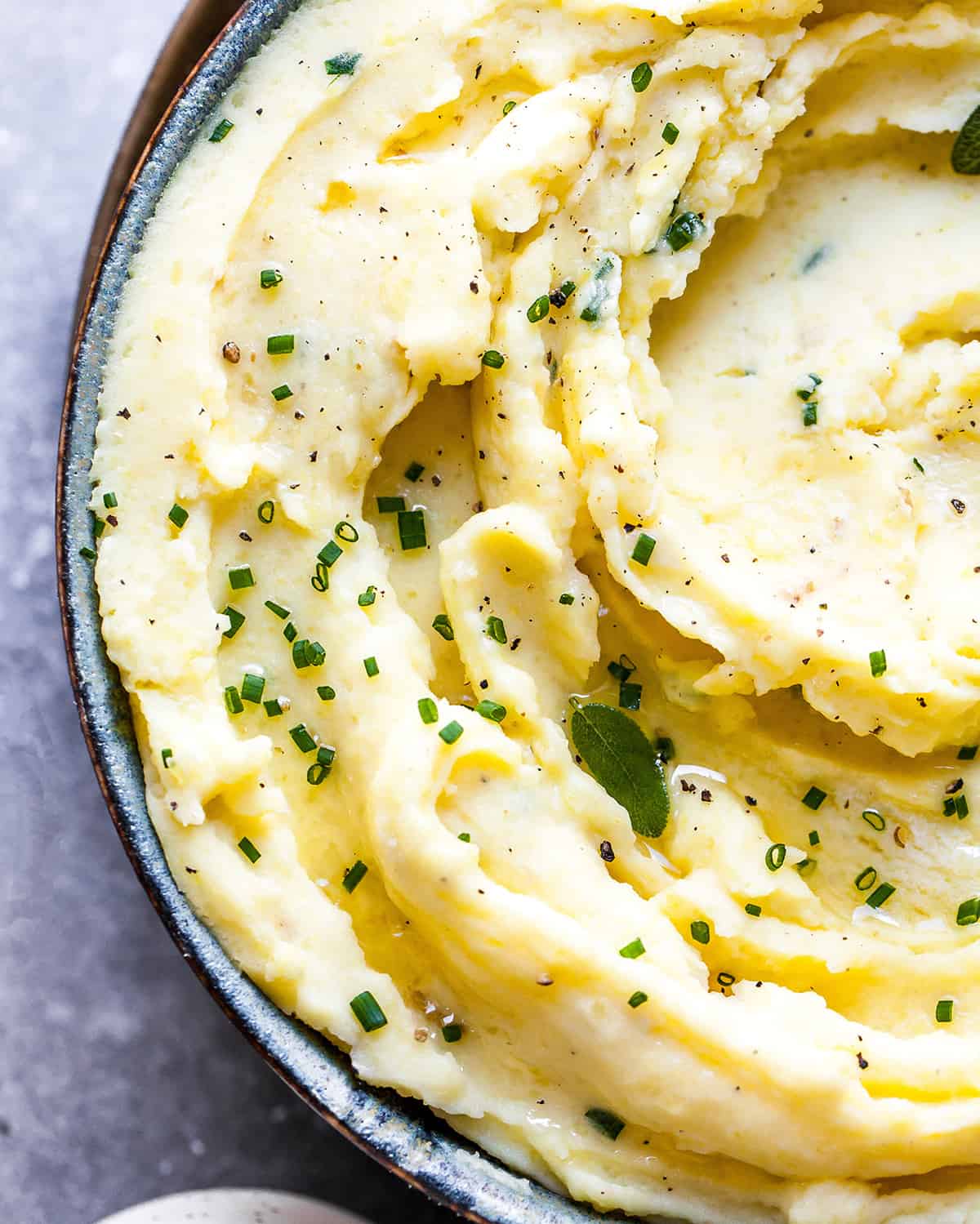 Overhead view of mashed potatoes in a bowl topped with fresh herbs