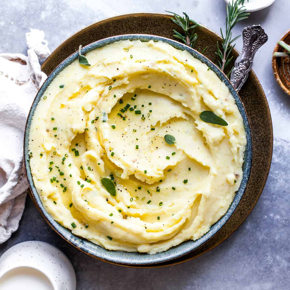 These herb-infused garlic mashed potatoes are the best mashed potatoes you will ever eat. They are creamy, fluffy buttery and so insanely delicious you will never make another mashed potatoes recipe again. Plus they're easy to make and can be prepared ahead of time! Overhead view of mashed potatoes in a bowl topped with fresh herbs