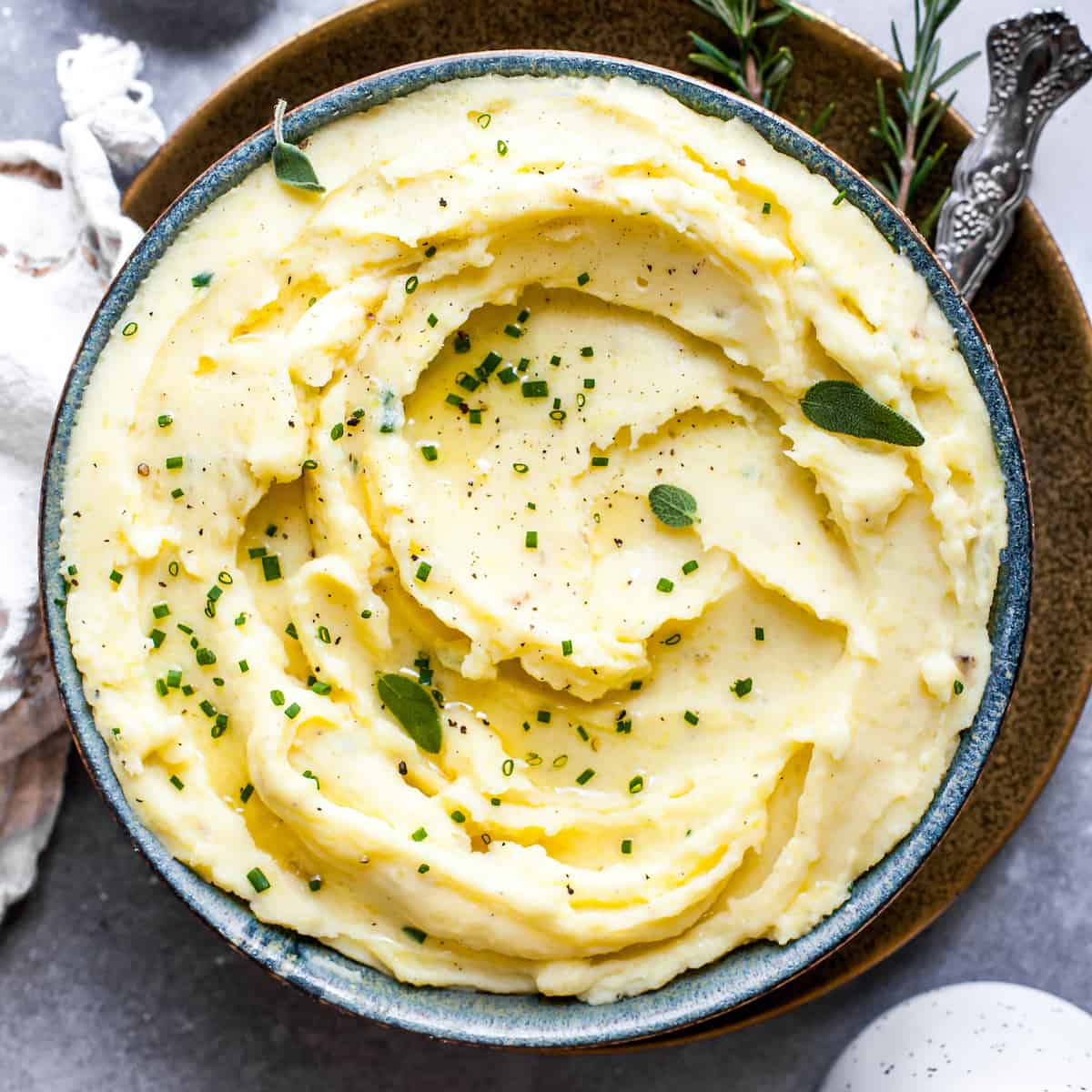Overhead view of mashed potatoes in a bowl topped with fresh herbs