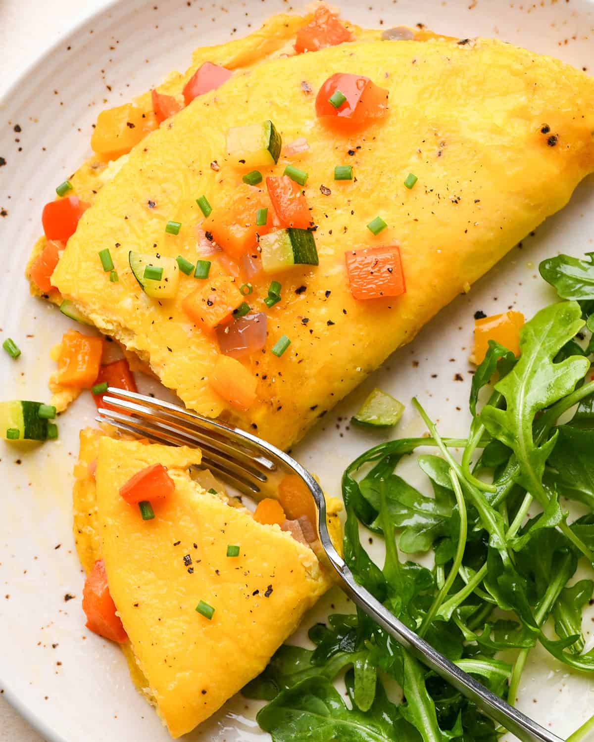 a vegetable omelette on a plate with a fork taking a bite 