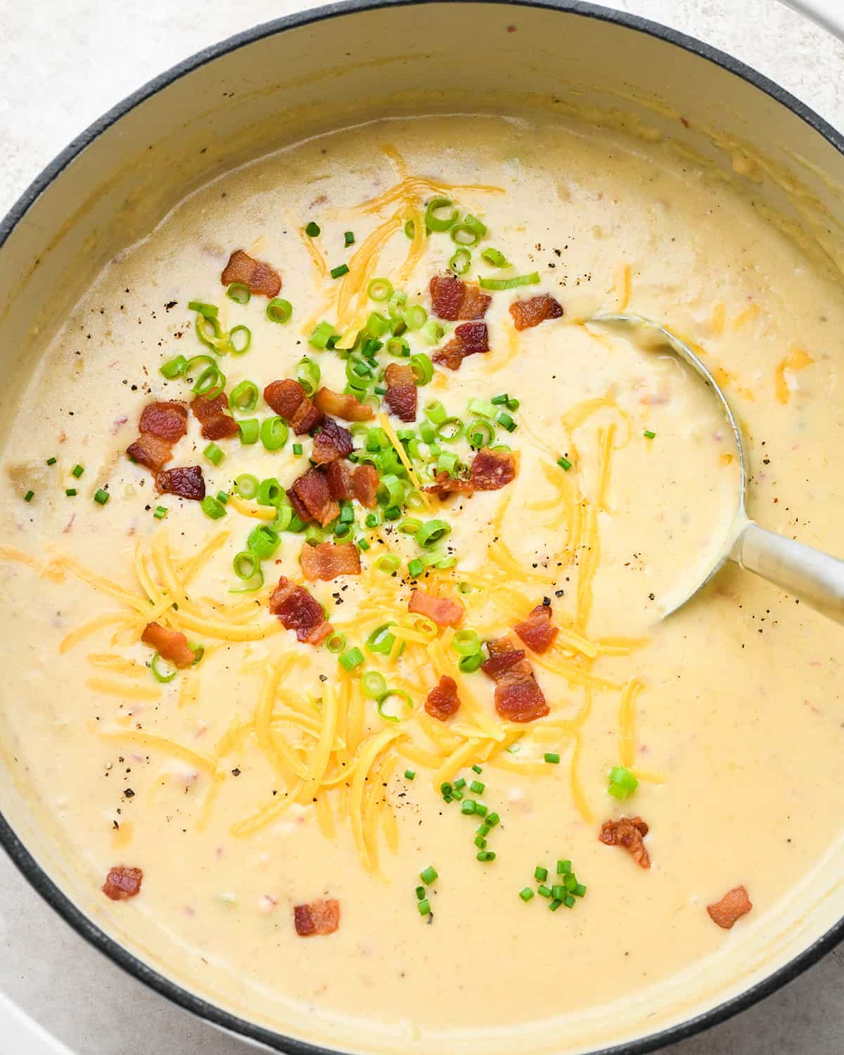 Potato Soup being ladled out of a dutch oven. 