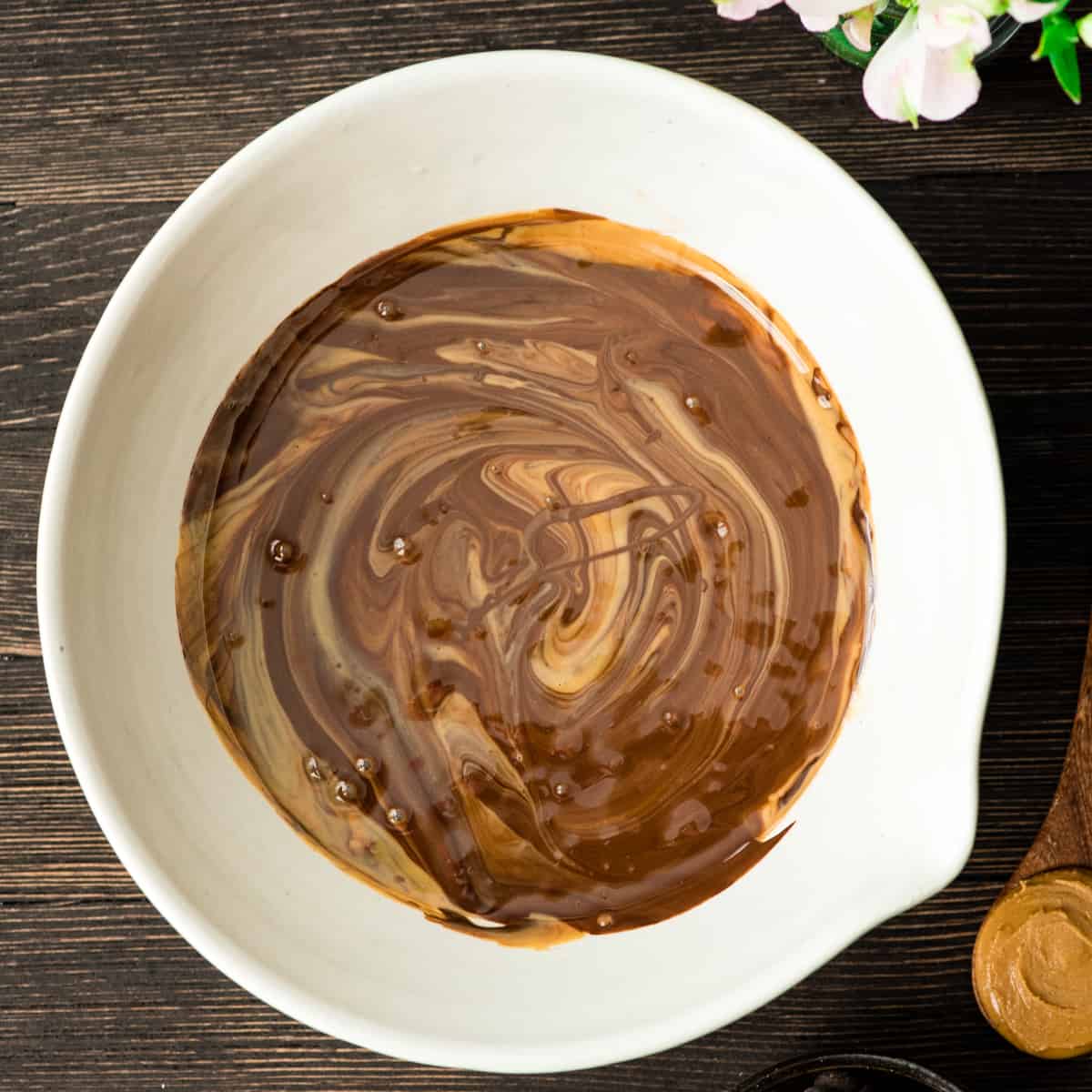 overhead photo showing how to make puppy chow - stirring melted chocolate and peanut butter