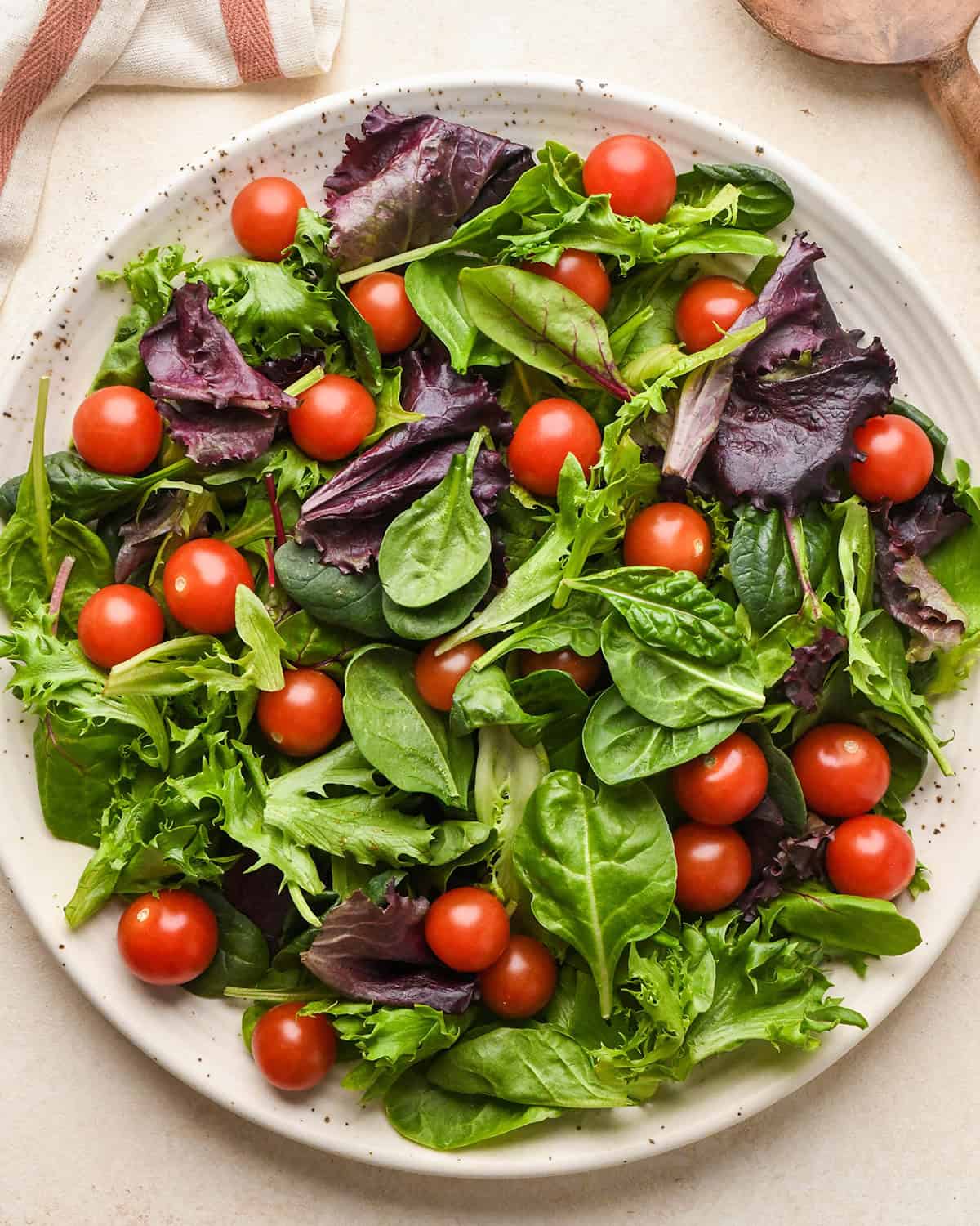how to assemble burrata salad - tomatoes and spring mix on a plate
