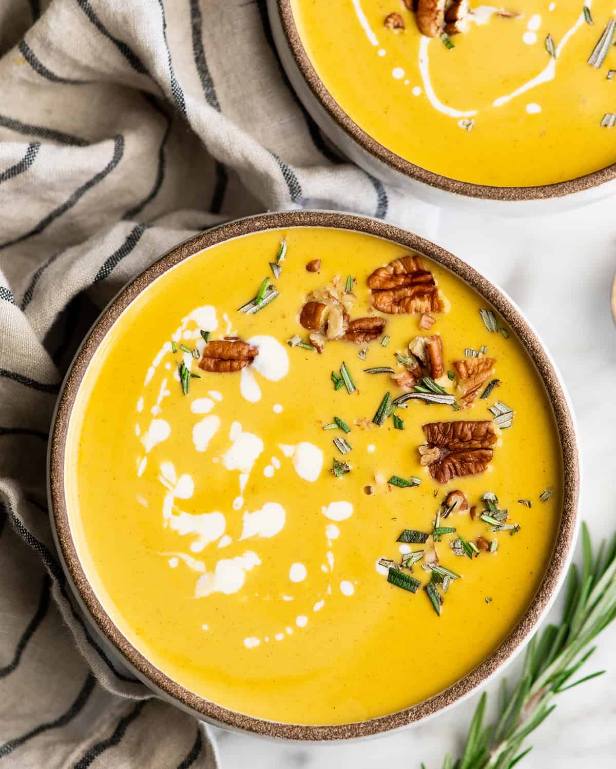 Overhead view of a bowl of butternut squash soup with cream, herbs and nuts 