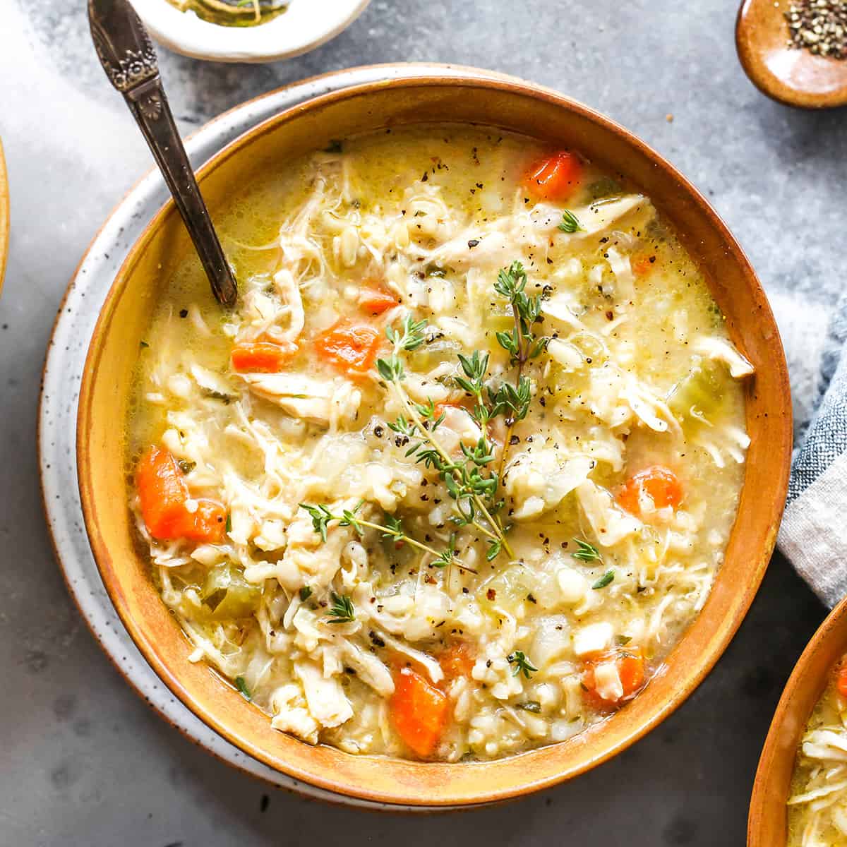 a bowl of Chicken and Rice Soup with a spoon garnished with thyme
