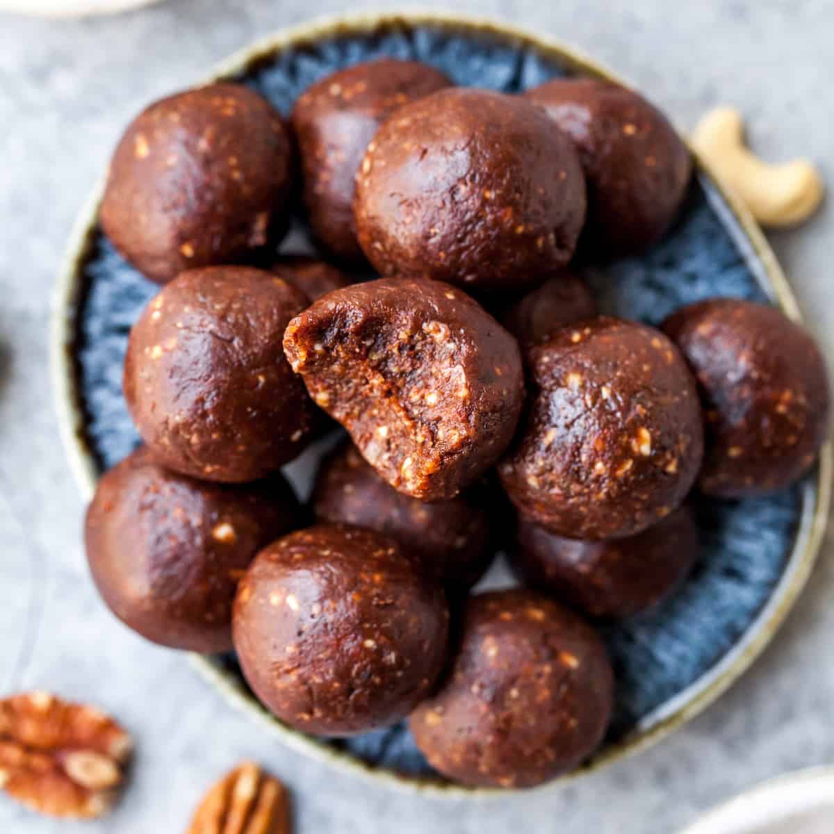 Chocolate Date Energy Balls on a plate, one has a bite taken out of it