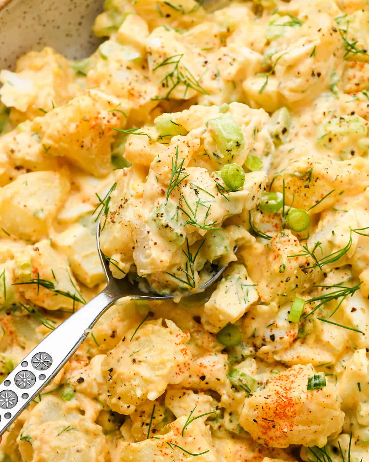 a spoon taking a scoop of potato salad