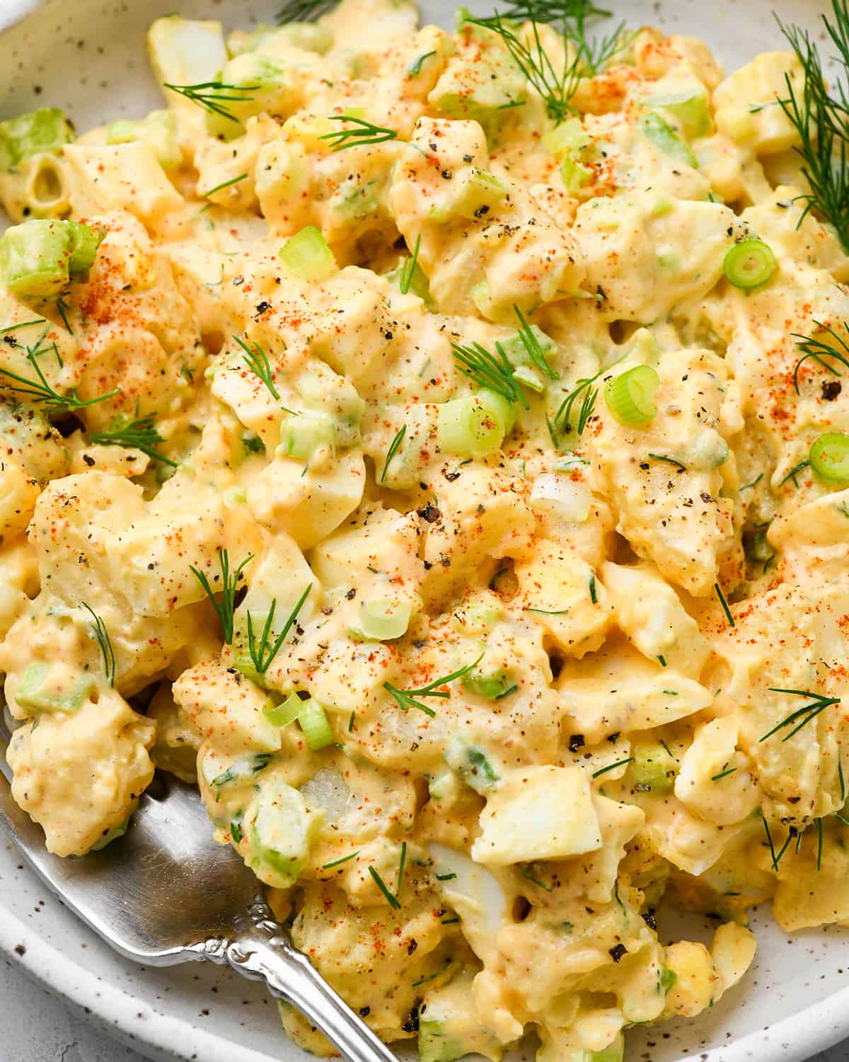 up close photo of potato salad on a plate with a fork