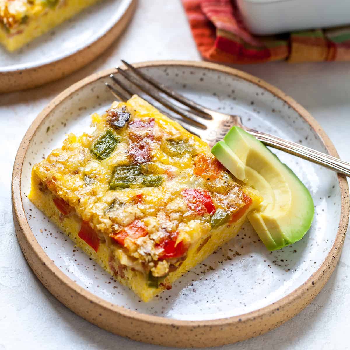 This Egg Casserole (Egg Bake) is an easy breakfast casserole that's made with only 9 ingredients (eggs, veggies, bacon, cheese and seasoning)! It's a healthy, low-carb way to start the day! #eggcasserole #breakfastcasserole #bacon #eggs #breakfast #brunch #recipe #joyfoodsunshine front view of a piece of egg casserole on a plate