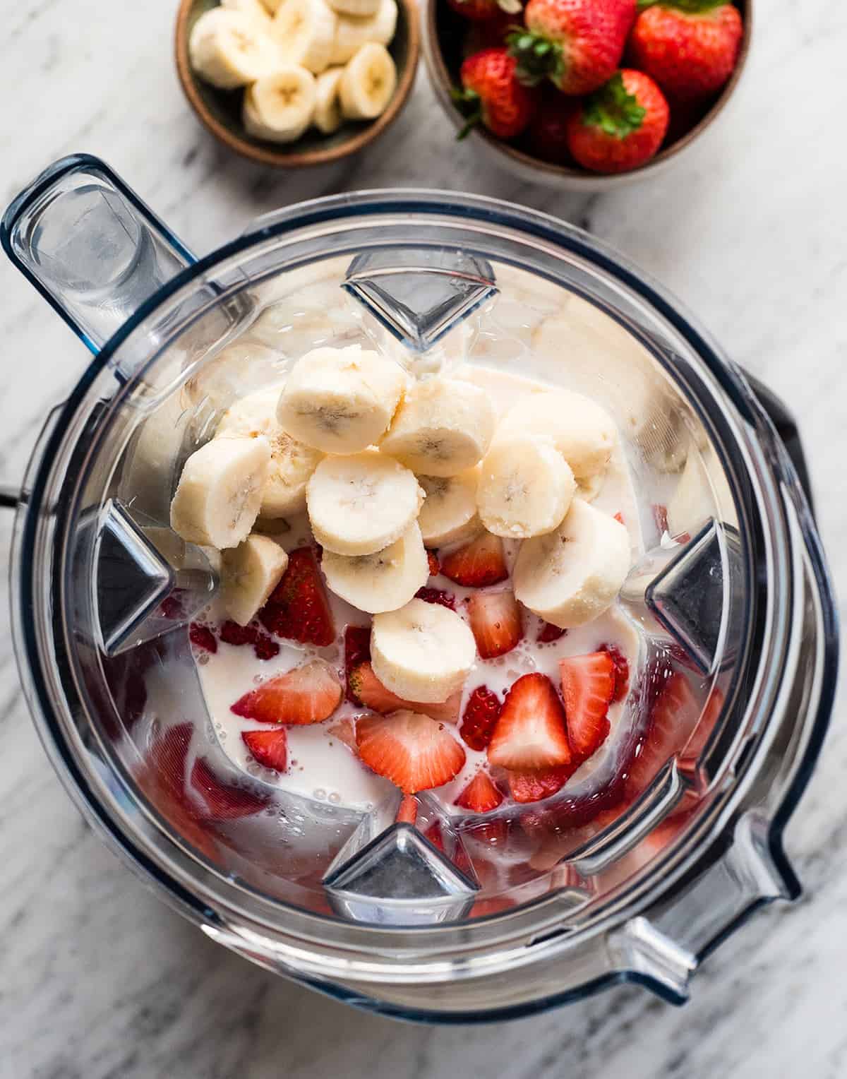 overhead view of the ingredients in this strawberry banana smoothie recipe in the vitamix before blending