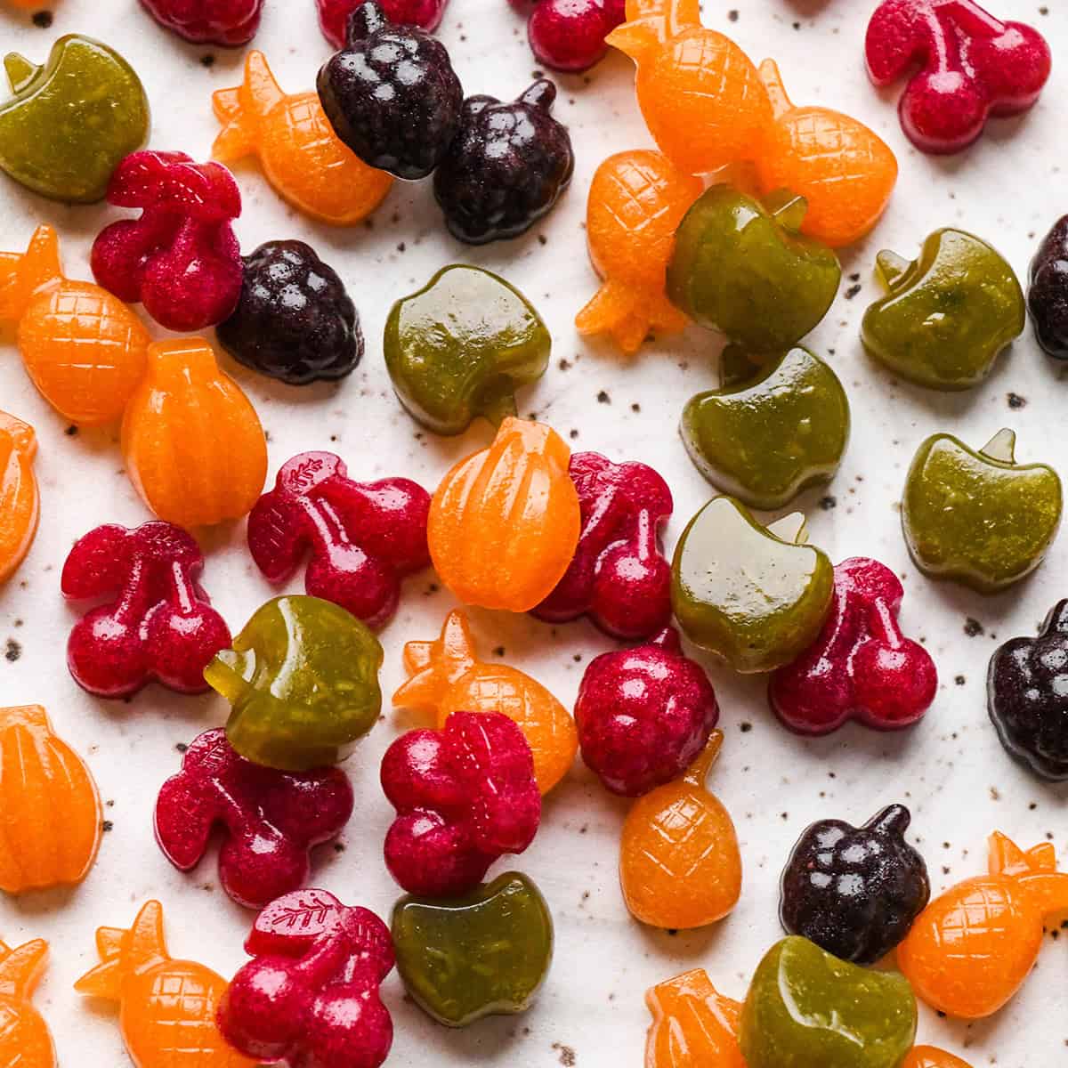 Homemade Fruit Snacks recipe made with whole fruits & vegetables! A healthy, high-protein snack loaded with nutrients made in the blender! #paleo #glutenfree #grainfree #dairyfree #refinedsugarfree #healthysnack #fruitsnacks #homemade #kidfriendly #snacktime a pile of red, green, purple and orange Homemade Fruit Snacks