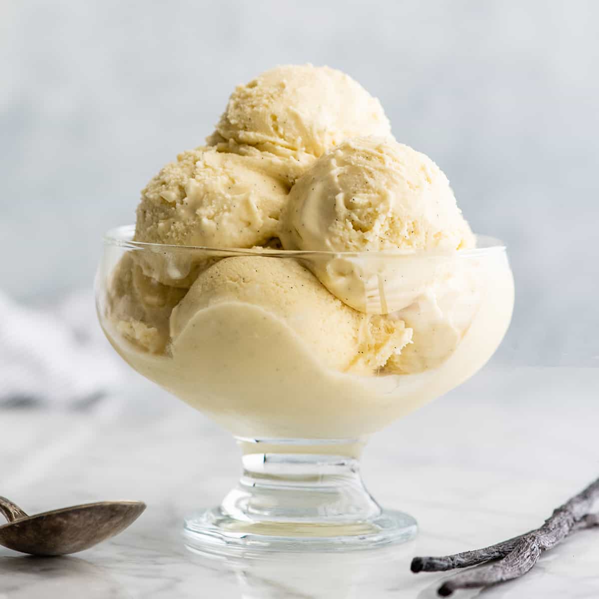 front view of a glass dish with scoops of vanilla ice cream inside