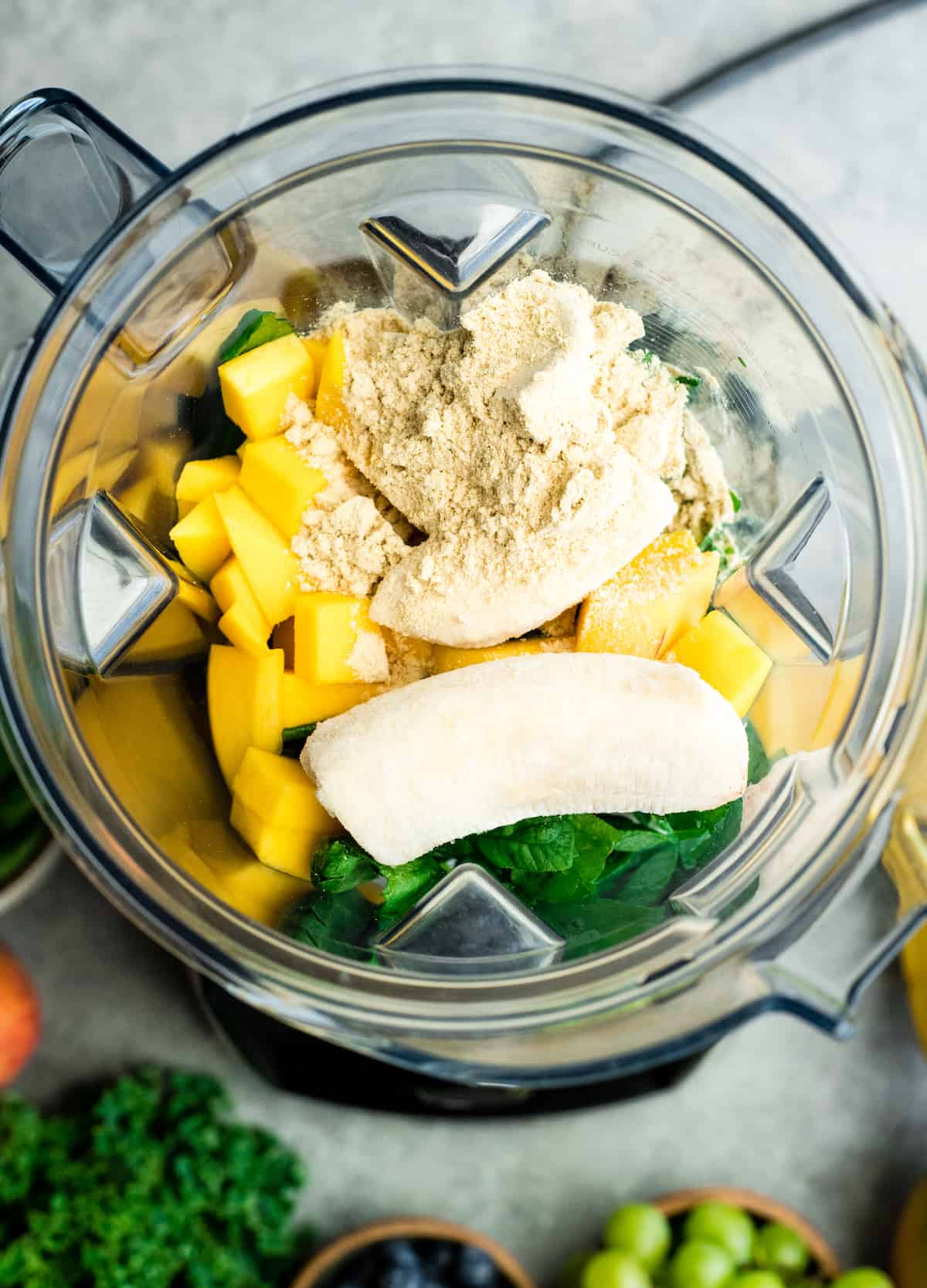 overhead view of all the ingredients for this Green Smoothie Recipe in the container of a vitamix blender before blending. 