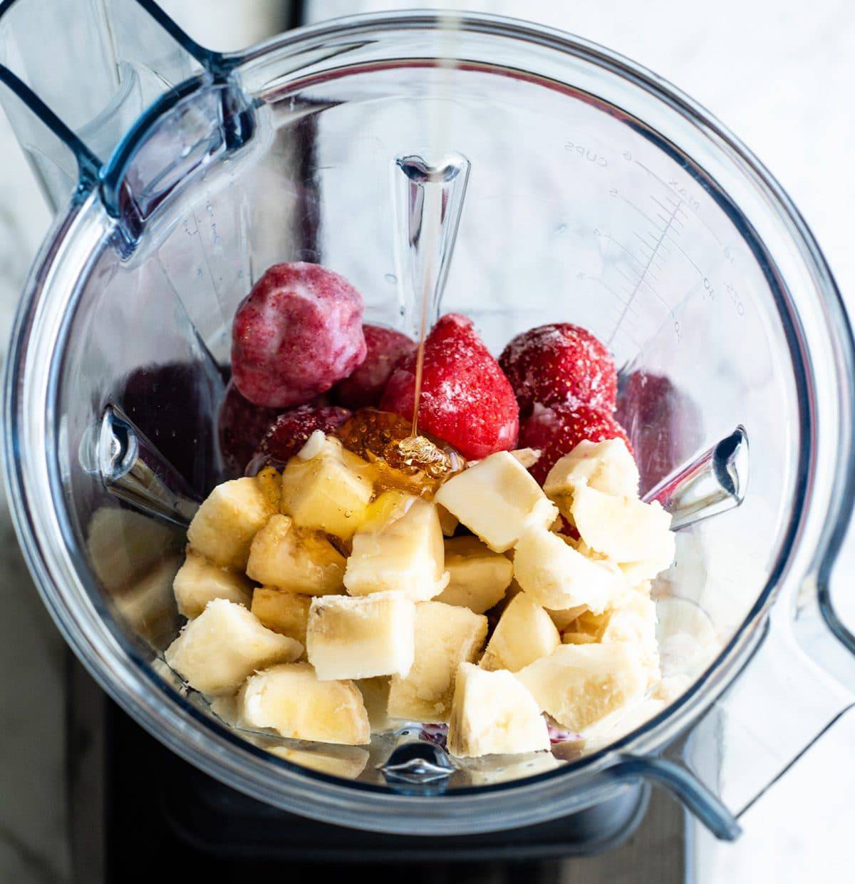overhead photo showing how to make a smoothie bowl - adding honey