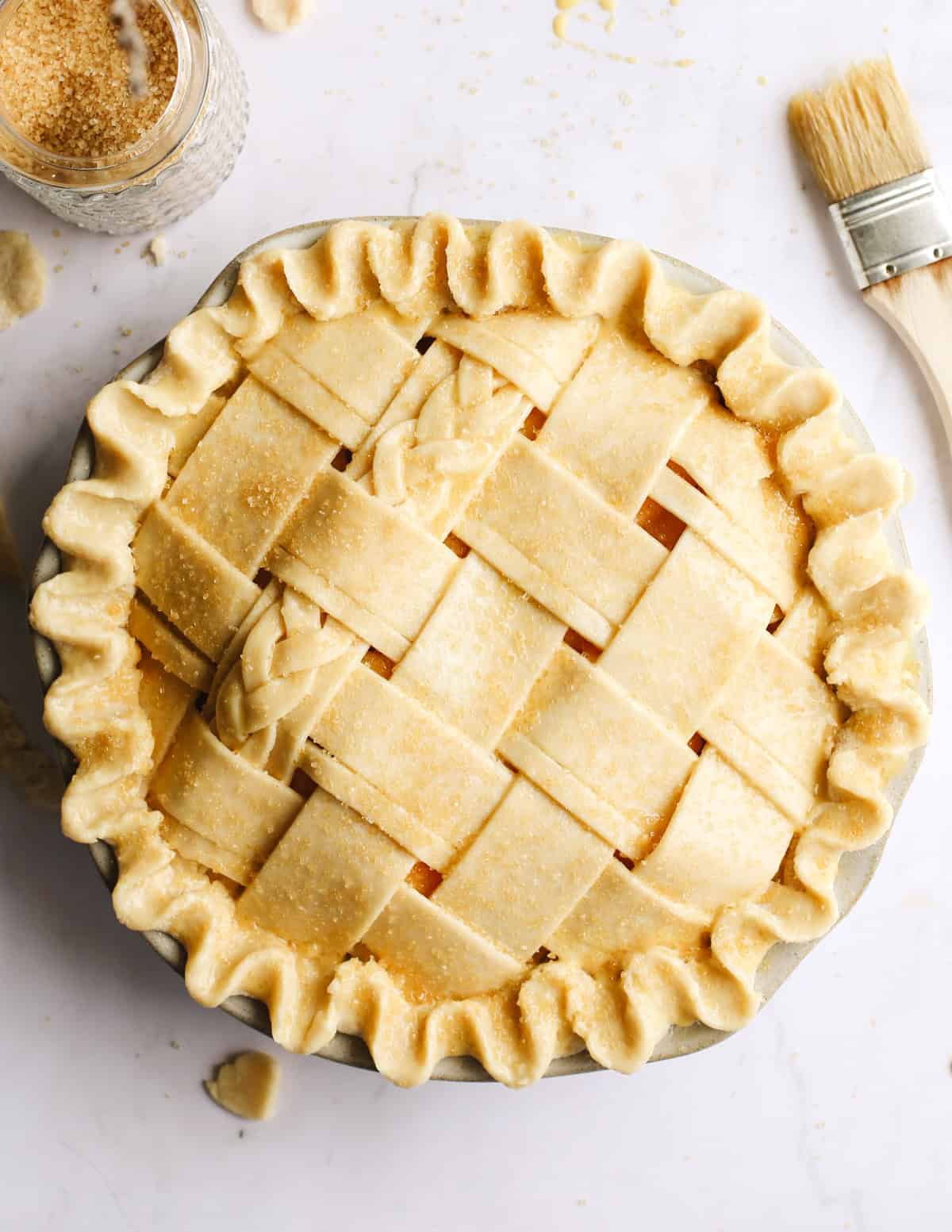 overhead photo of a Butter Pie Crust in a lattice pattern before baking with an egg wash and raw sugar