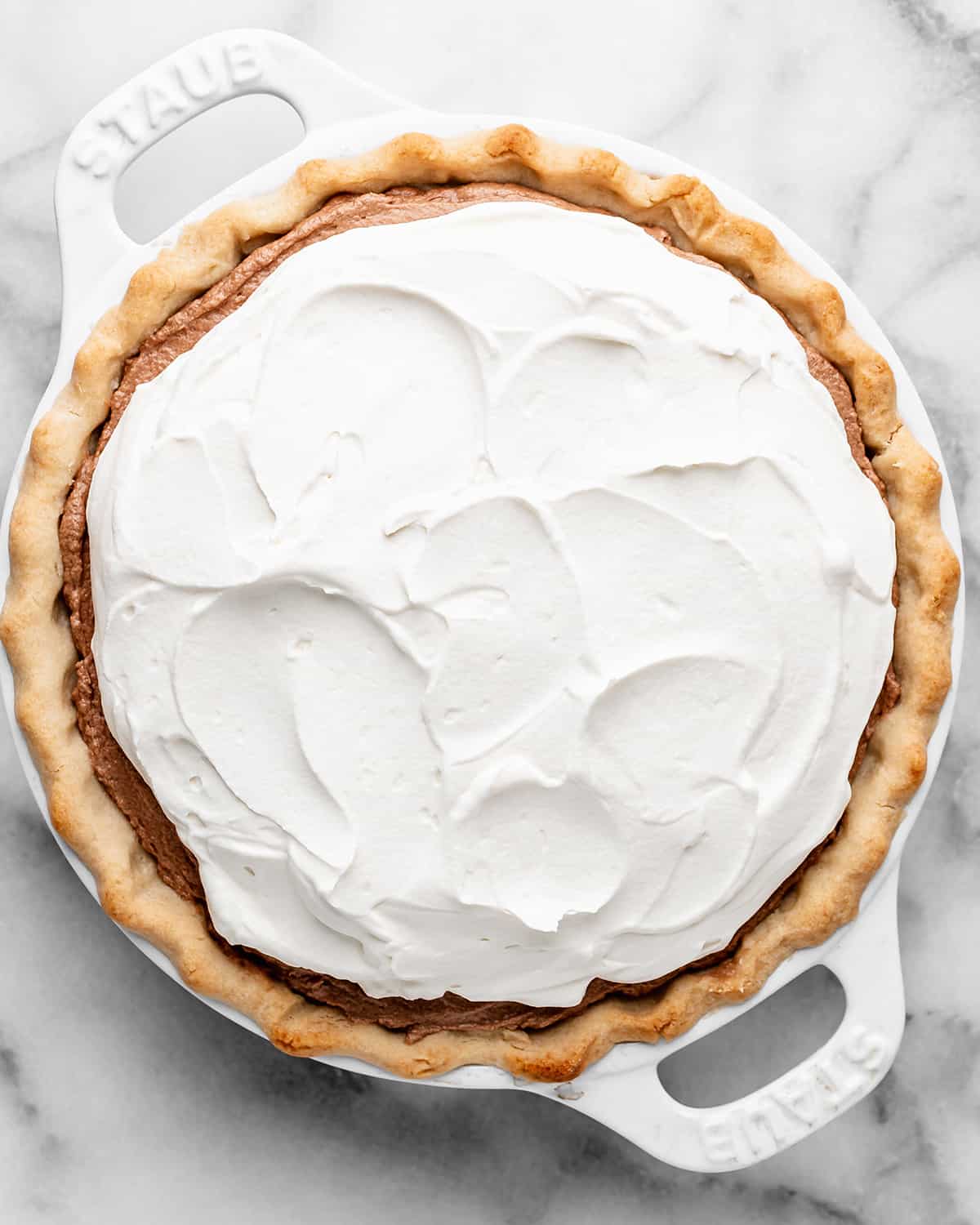 assembling french silk pie - spreading whipped cream on top of chocolate 