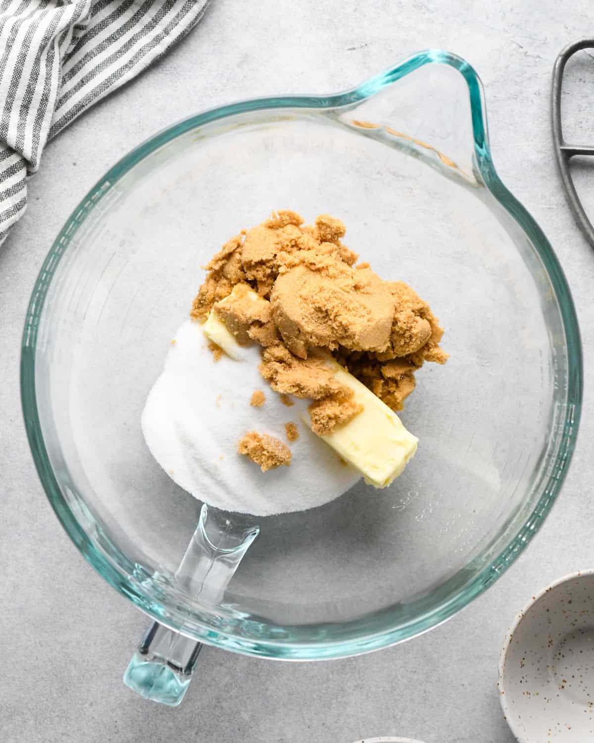making chocolate chip oatmeal cookies -butter and sugar is a glass mixing bowl with a striped towel in the top left corner