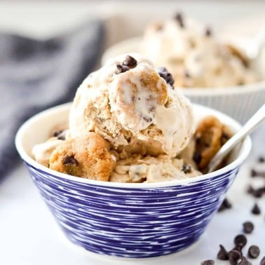 front view of a bowl of paleo cookie dough ice cream in a bowl with a spoon and chunks of cookie dough
