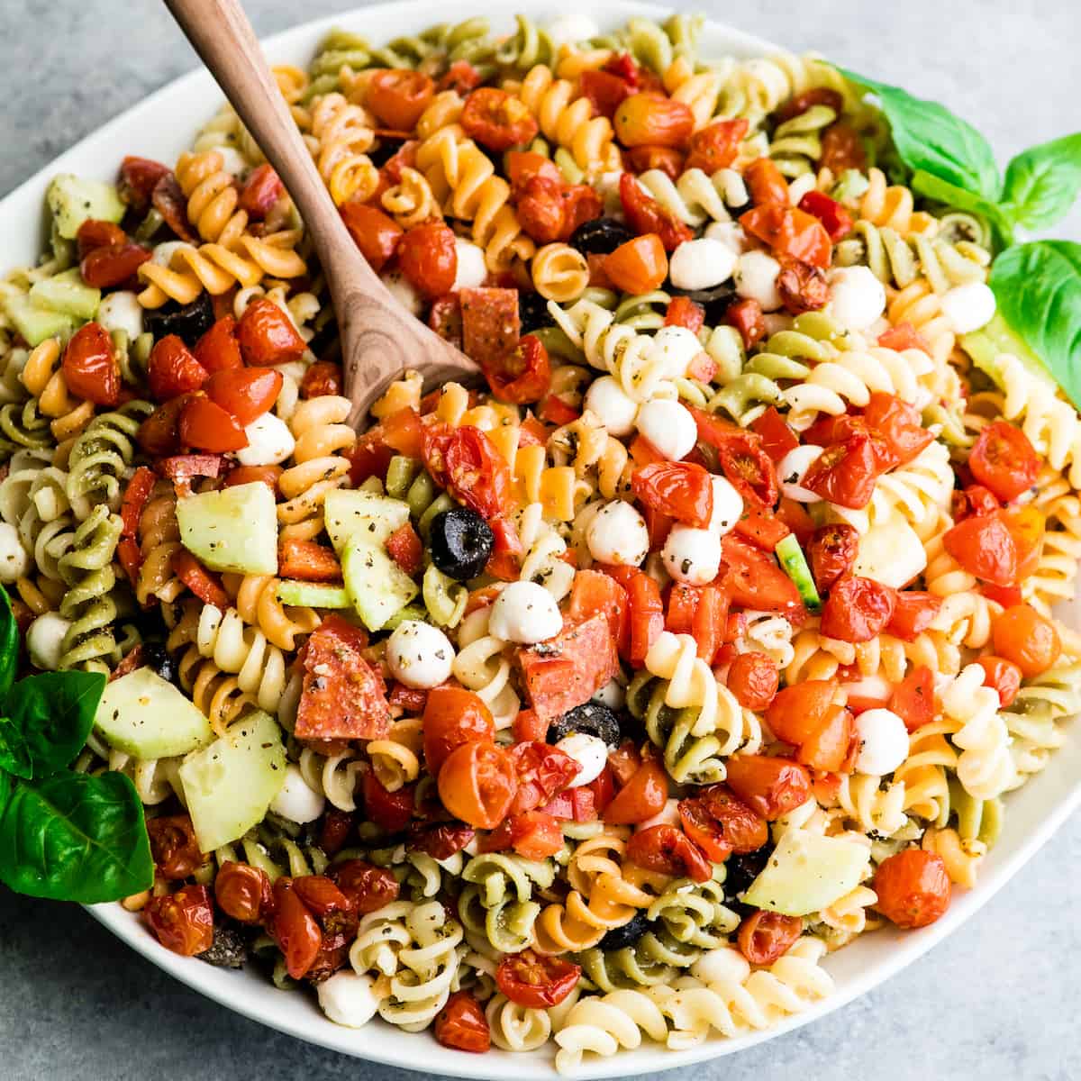 This Best Pasta Salad Recipe is made with Homemade Dressing & Roasted Tomatoes! It is the perfect healthy & flavorful make-ahead BBQ side dish full of fresh veggies, pepperoni and fresh mozzarella cheese! #pastasalad #bbq #sidedish #bestpastasalad #pastasaladrecipe #recipe #healthyrecipe #easypastasalad #homemadedressing overhead view of the best pasta salad recipe in a large white serving bowl