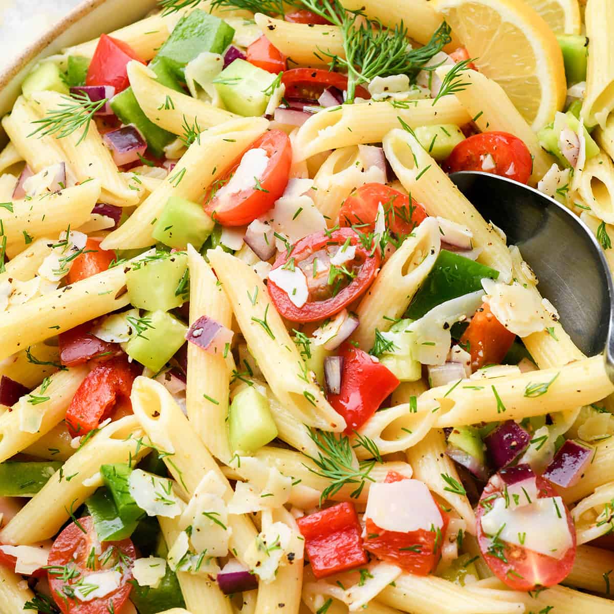 a spoon taking a scoop of lemon pasta salad out of a bowl