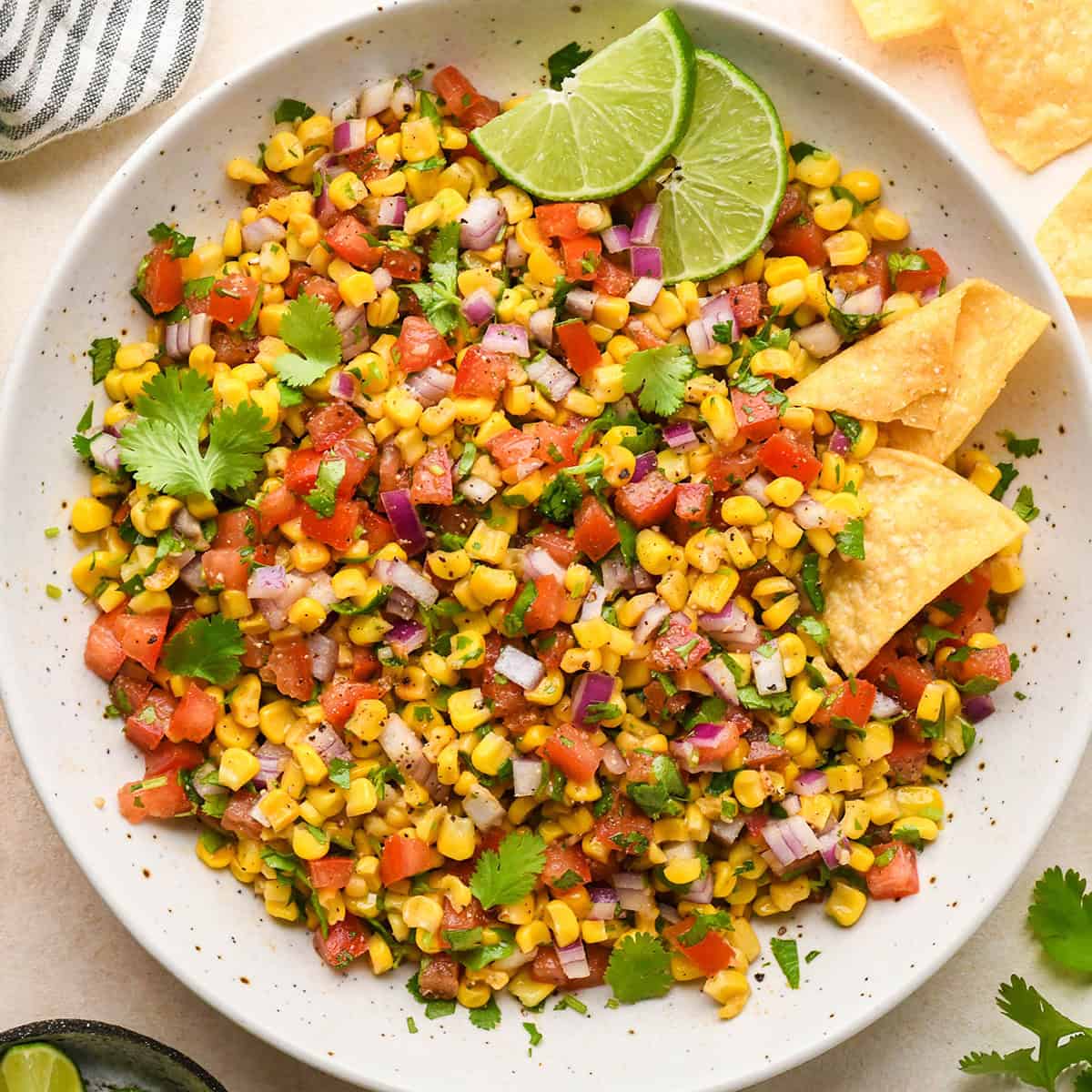 sweet Corn Salsa in a bowl with chips and limes