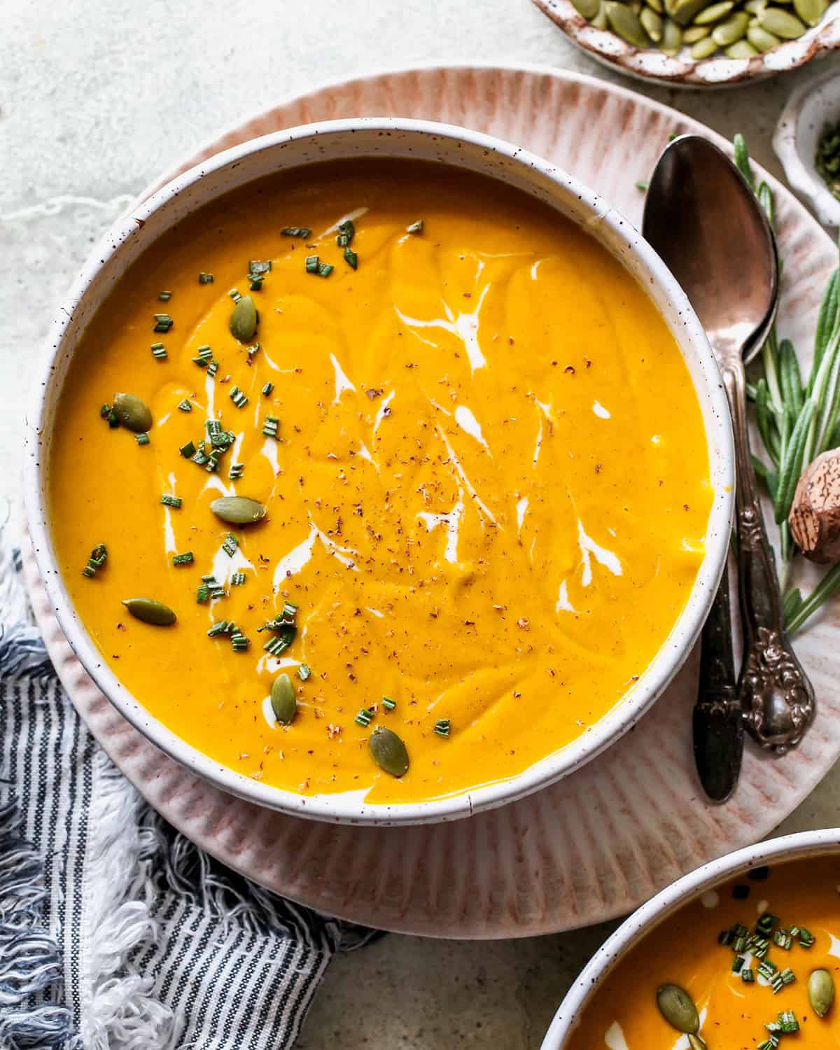 a bowl of Sweet Potato Soup garnished with rosemary, cream and seeds. 