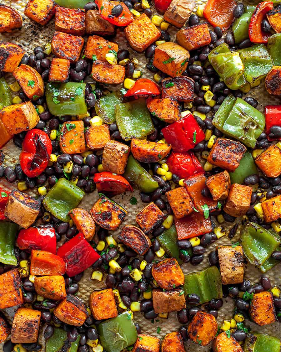 These healthy black bean sweet potato tacos are the best vegetarian tacos ever. Sweet potatoes and vegetables are perfectly spiced and roasted, then tossed with a honey, lime cilantro mixture for the most flavorful and delicious tacos. Taco night isn't complete without this sweet potato taco recipe! black bean sweet potato tacos on a baking sheet after roasting