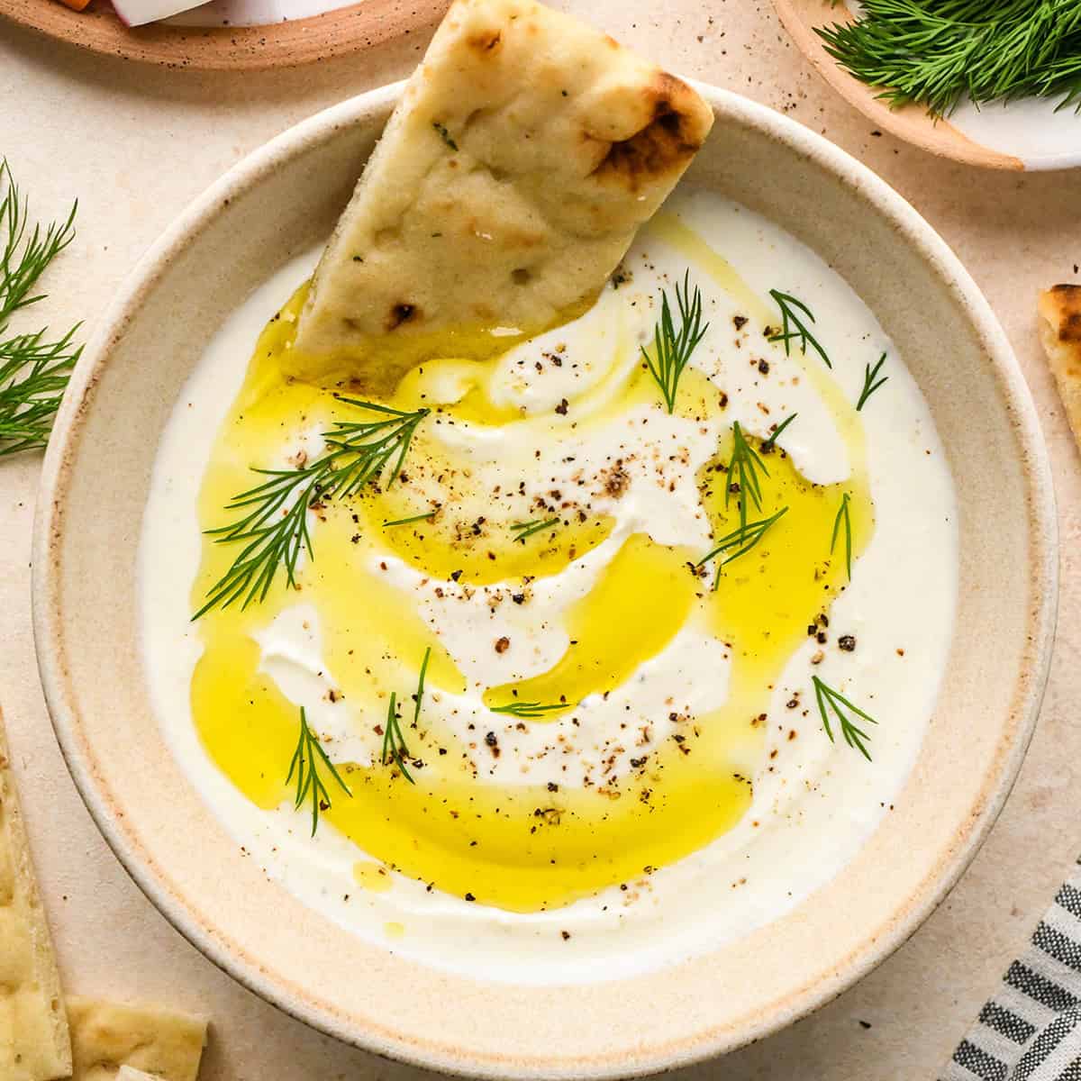 Whipped Feta Cheese Dip in a bowl garnished with dill and olive oil